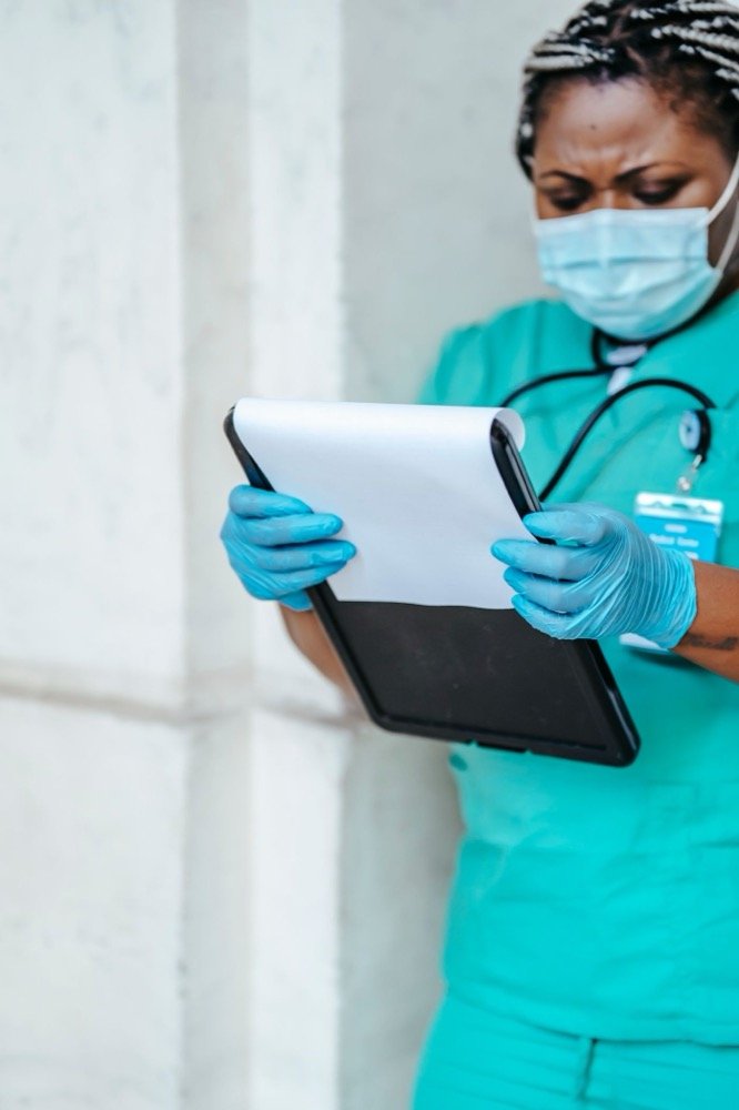 Operatrice sanitaria con guanti consulta documenti su un tablet